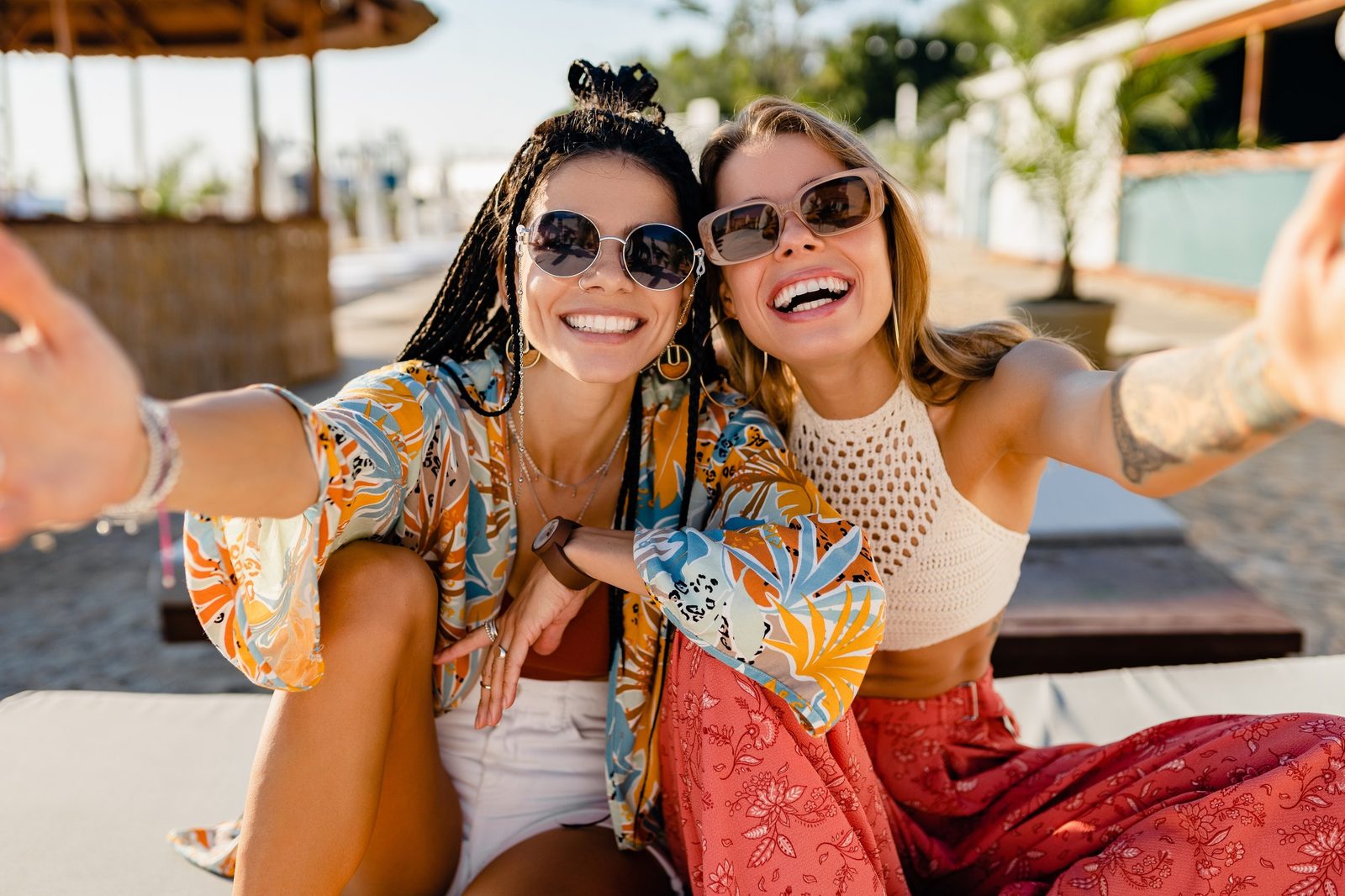 Two women smiling together in sunglasses outdoors