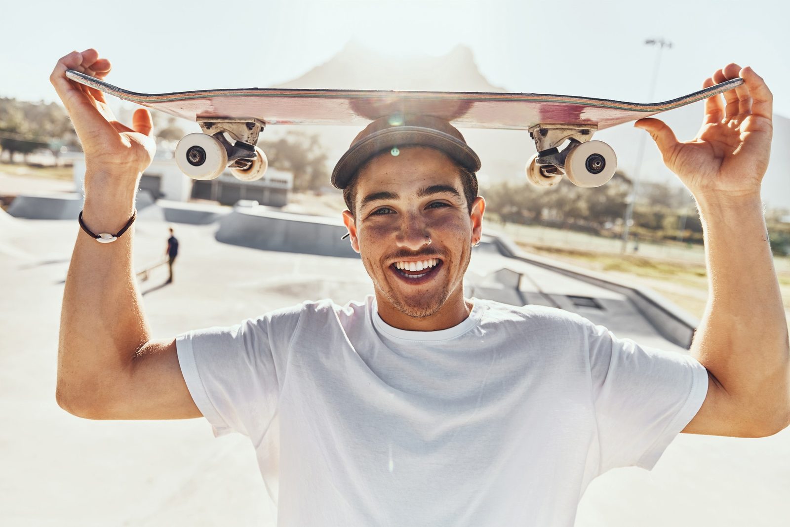 Smiling skateboarder holding a skateboard overhead outdoors