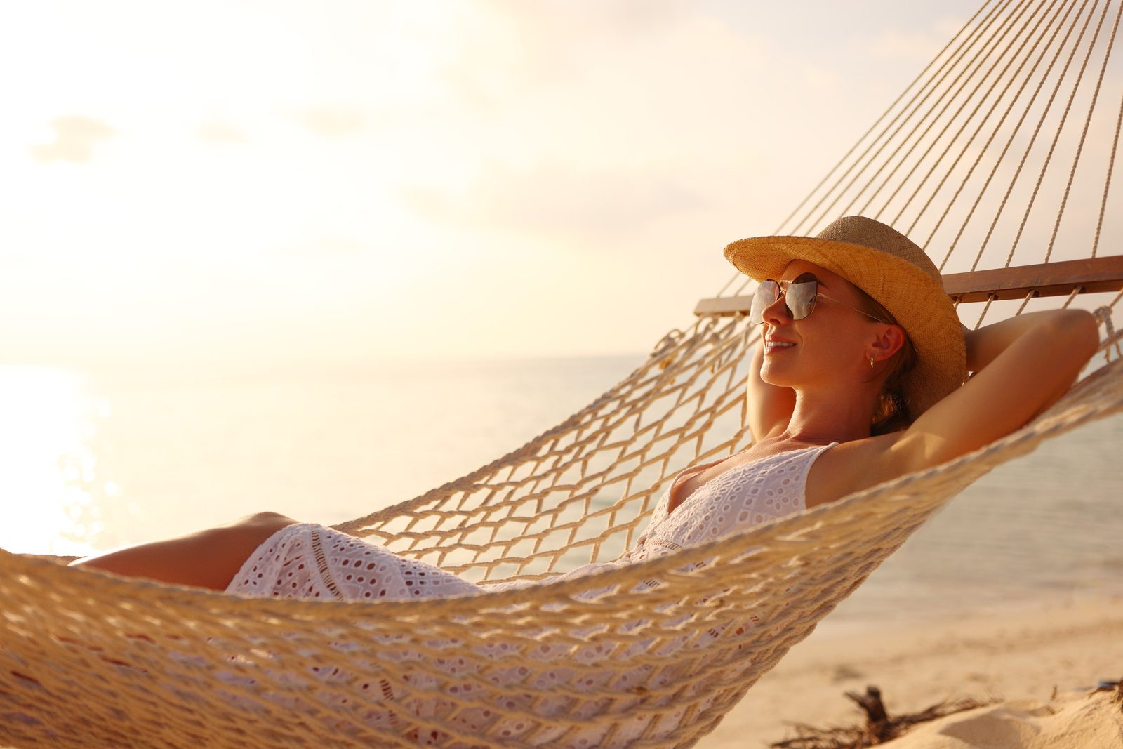 Woman relaxing in a hammock at the beach wearing sunglasses